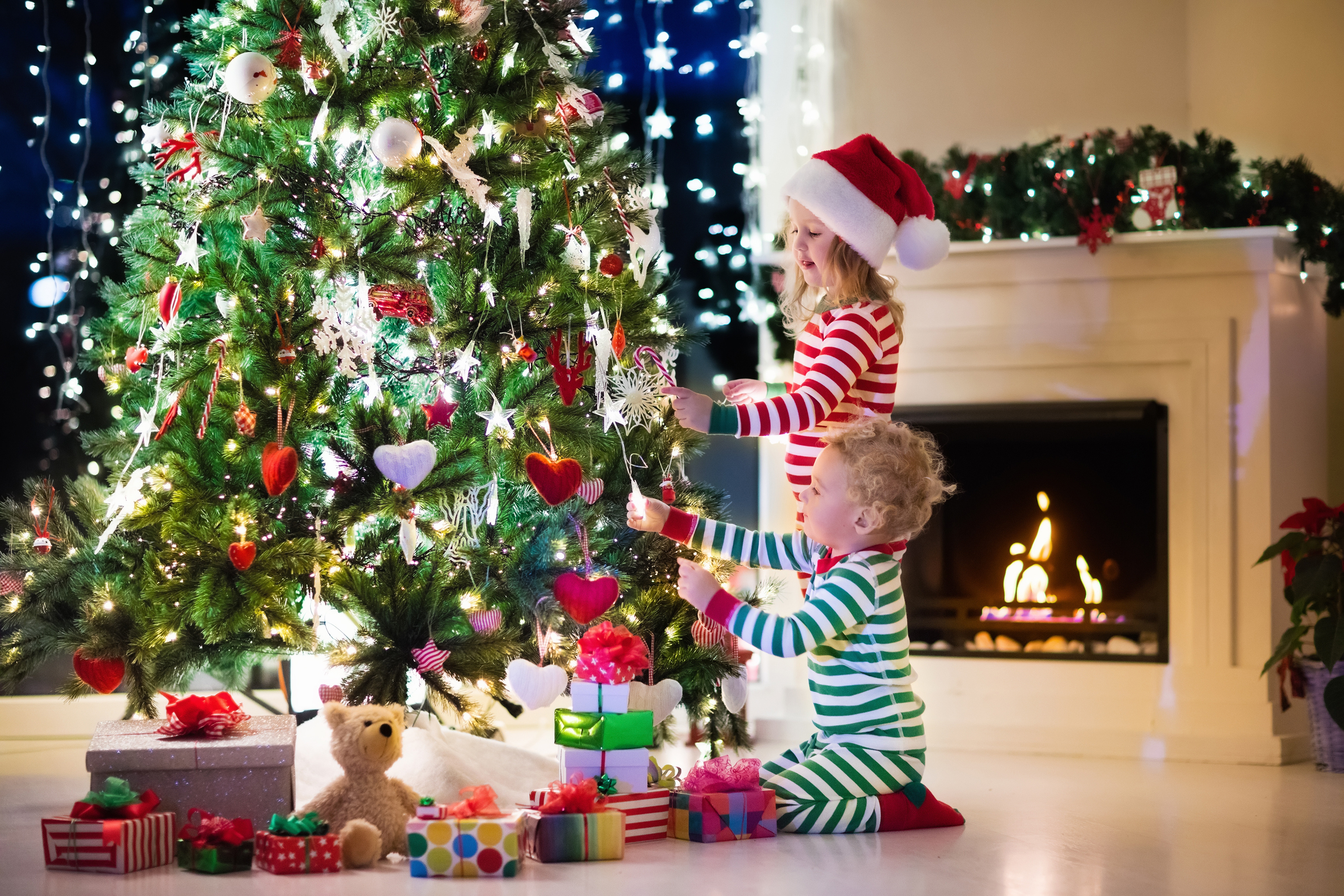 Рождество праздник детей. Елка Новогодняя украшенная. Подарки для елки. Дети наряжают елку. Красивая елка с подарками.